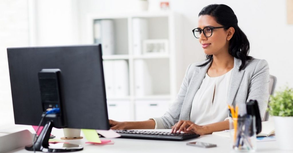 woman sitting at desk in front of computer | 10 Reasons to Hire a Freelance Writer for Your Small Business Website